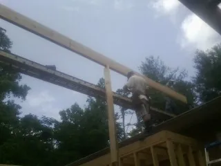 Carpenter setting a ridge beam over a new addition frame — Ice Dam Removal by Roofing Brothers in Elon