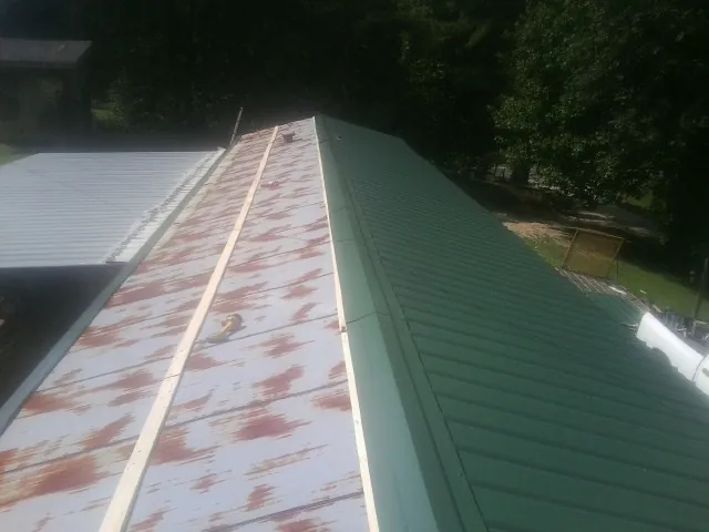 Old rusted panels beside newly installed green metal roofing — Wind Damage Roof Repair by Roofing Brothers in Elon
