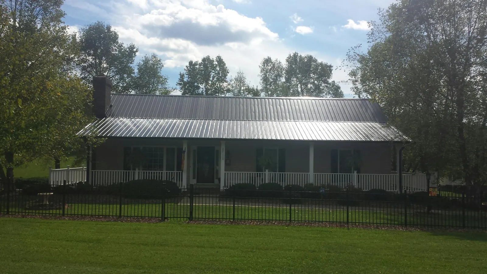 Gray metal roof on a brick ranch with a full width front porch — Gutter Guard Installation work by our crew in Elon