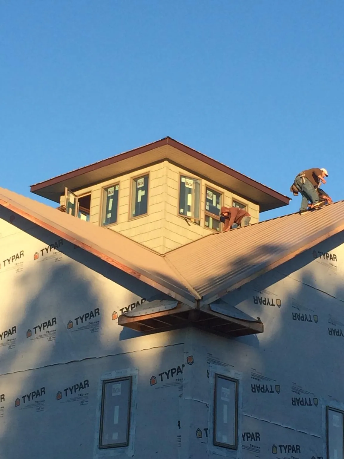 Roofers working around a rooftop cupola on a new metal roof at sunset — Roof Waterproofing in Elon by Roofing Brothers